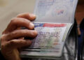 FILE PHOTO: A member of the Al Murisi family, Yemeni nationals who were denied entry into the U.S. because of the travel ban, shows the cancelled visa in their passport from their failed entry to reporters as they successfully arrive to be reunited with their family at Washington Dulles International Airport in Chantilly, Virginia, U.S., February 6, 2017.  REUTERS/Jonathan Ernst/Files
